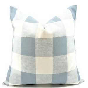 Op de afbeelding: Een vierkant decoratief kussen met een groot blauw-wit geblokt patroon. Het kussen heeft een zachte, getextureerde uitstraling en is ontworpen voor woondecoratie. Het kleurenschema is lichtblauw en gebroken wit. Afmetingen ca. 40 cm x 40 cm.