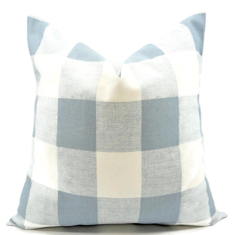 Op de afbeelding: Een vierkant decoratief kussen met een groot blauw-wit geblokt patroon. Het kussen heeft een zachte, getextureerde uitstraling en is ontworpen voor woondecoratie. Het kleurenschema is lichtblauw en gebroken wit. Afmetingen ca. 40 cm x 40 cm.