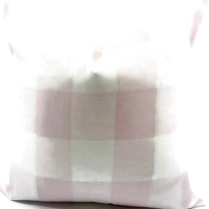 May include: A white pillow with a pink and white buffalo plaid pattern.