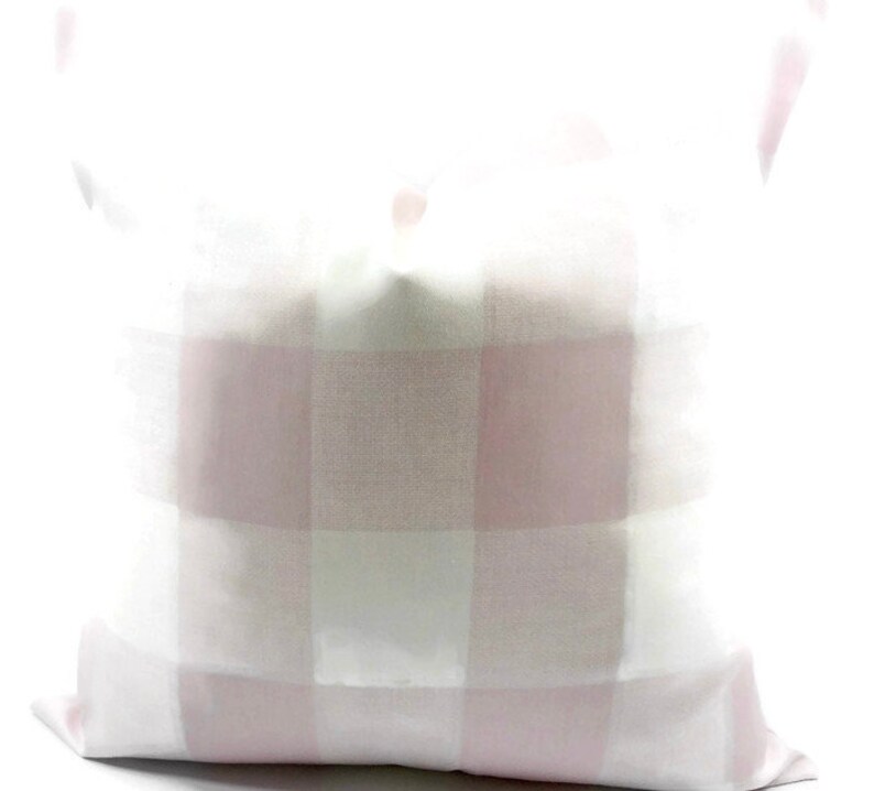 May include: A white pillow with a pink and white buffalo plaid pattern.