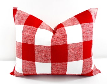 May include: Red and white buffalo check pillow cover. The pillow cover is made of a soft, textured fabric.