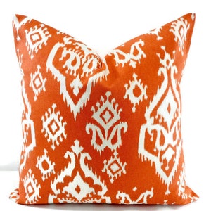 May include: Orange and white throw pillow with an ikat pattern.