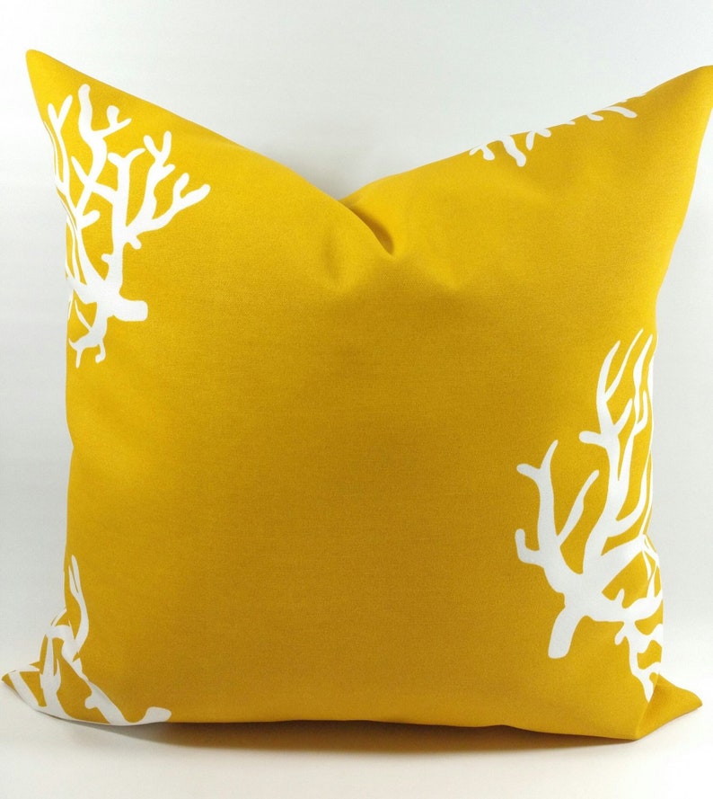 May include: A yellow throw pillow with a white coral reef design.