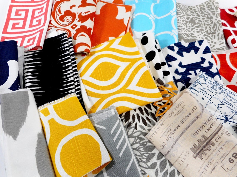 May include: A collection of fabric swatches featuring a variety of patterns and colours, including yellow, blue, red, black and white. The swatches are arranged randomly and some have text printed on them, including "GRANDE MAISON DE PARIS" and "TISSE SON LINGE ELLE".