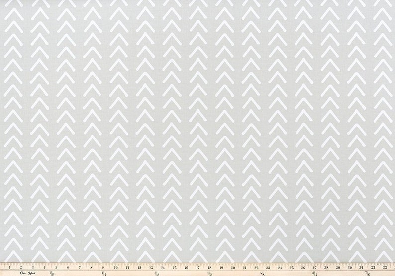May include: A light gray fabric with a repeating pattern of white chevrons pointing upwards. The chevrons are evenly spaced and create a textured appearance. The fabric is suitable for various crafting and sewing projects.