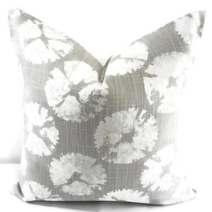 May include: A gray and white floral patterned throw pillow. The pillow is made of a soft, textured fabric and features a subtle sheen.
