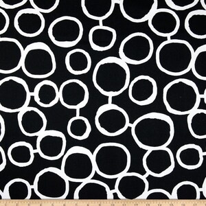May include: Black and white fabric with a repeating pattern of large, white circles on a black background.
