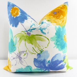 May include: A white pillow with a floral pattern in shades of blue, yellow, and green. The flowers are stylized and have a watercolor effect.