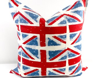 May include: Square throw pillow featuring a distressed Union Jack design. The pillow has a white background with a pattern of red crosses and blue diagonal lines. The pillow is a decorative home accent.
