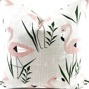 May include: A white pillow with a pink flamingo and green leaf pattern. The pillow is made of a soft, textured fabric.