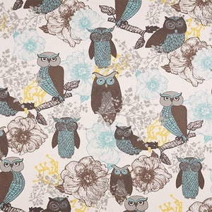 May include: A white fabric with a repeating pattern of brown and blue owls on branches with light blue and brown flowers. The owls have brown bodies and blue wings.
