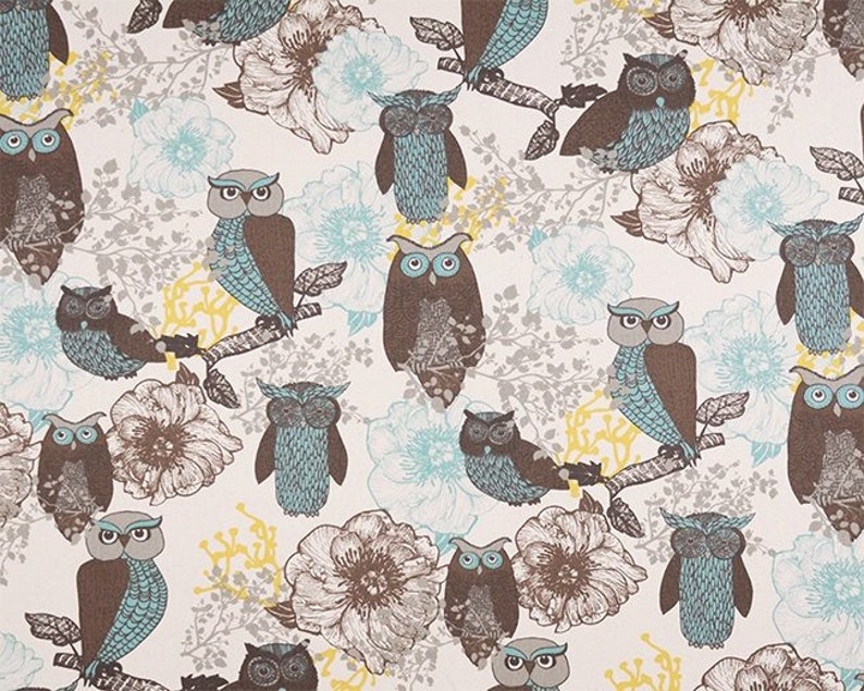 May include: A white fabric with a repeating pattern of brown and blue owls on branches with light blue and brown flowers. The owls have brown bodies and blue wings.