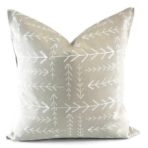 May include: A gray throw pillow with a white arrow and tree pattern.