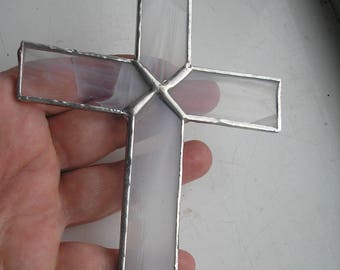 May include: A white stained glass cross with a silver frame. The cross is hanging from a silver loop at the top.
