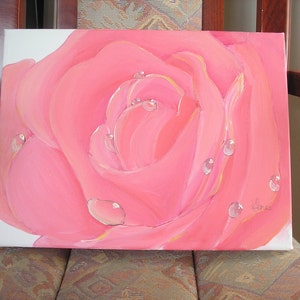 May include: A close-up painting of a pink rose with water droplets. The petals are a vibrant pink with subtle yellow highlights. The water droplets are clear and reflective, adding depth to the artwork. The painting is on a white canvas.