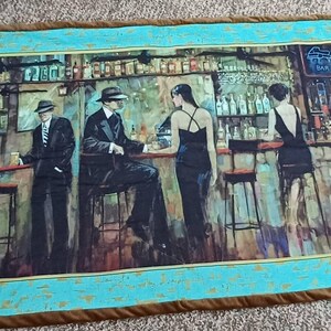 May include: A rectangular quilt featuring a bar scene with figures in vintage attire. The artwork depicts a bar with patrons and bartenders. The quilt has a teal border with a brown trim, creating a framed effect.