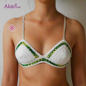 May include: White crochet bikini top with green and yellow trim. The top has a triangular shape and adjustable straps.