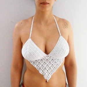 May include: White crochet halter top with a triangle design. The top features a halter neck and a detailed, openwork pattern at the bust and lower section. The top is made of a soft, textured yarn.