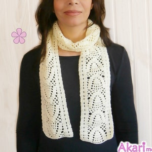 May include: A white crocheted scarf with a delicate pattern. The scarf is made with a fine yarn and has a soft, airy feel.