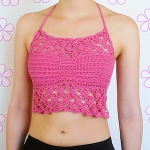May include: A pink crocheted halter top with a delicate lace pattern. The top is cropped and has a scalloped hem.