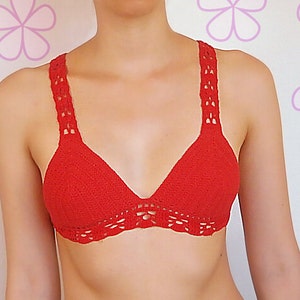 Op de afbeelding: Een rood gecrochet bikini-topje met een delicate kantversiering.