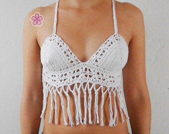 Könnte beinhalten: Weißes Häkel-Crop-Top mit Fransen-Details. Das Top hat einen V-Ausschnitt und dünne Träger.