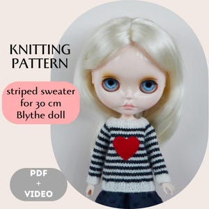 May include: A Blythe doll wearing a striped sweater with a red heart. The sweater has black and white stripes. The doll has blue eyes and blonde hair. The image includes the text "KNITTING PATTERN" and "striped sweater for 30 cm Blythe doll".