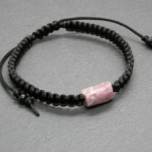 Peut inclure: Un bracelet en cordon tressé noir avec une perle de pierre précieuse rose et blanche.