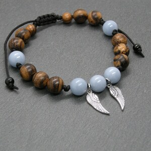 Peut inclure: Un bracelet avec des perles en bois brun et des perles de pierres précieuses bleu clair avec des breloques d'ailes d'ange argentées.