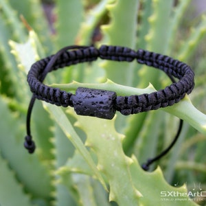 Pode incluir: Pulseira de cord&atilde;o preto com uma conta de rocha vulc&acirc;nica preta. A pulseira &eacute; ajust&aacute;vel com um n&oacute; deslizante.