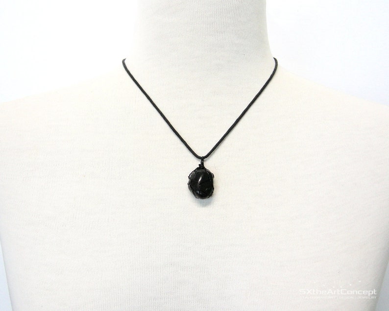 May include: A black gemstone pendant necklace with a black cord. The pendant is a rough, natural-looking stone.