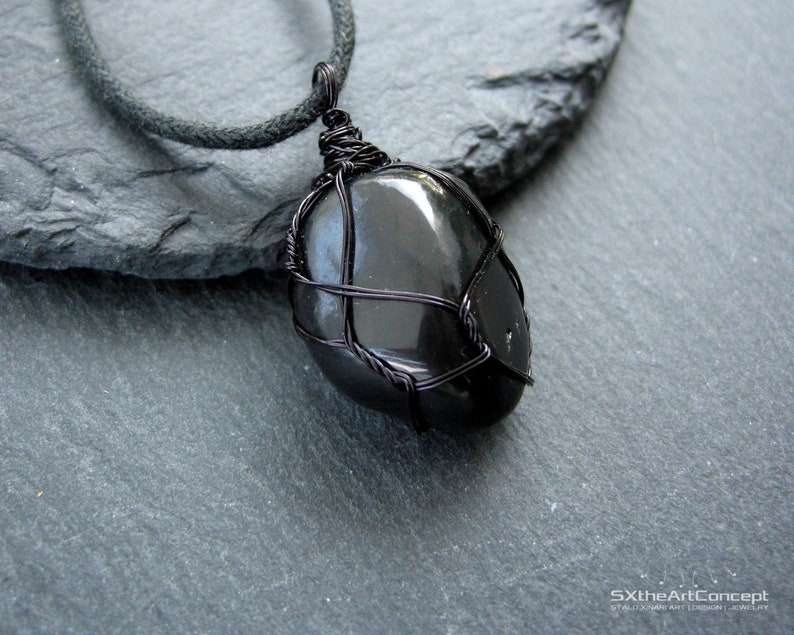 May include: Black onyx gemstone pendant wrapped in black wire, hanging from a black cord necklace.