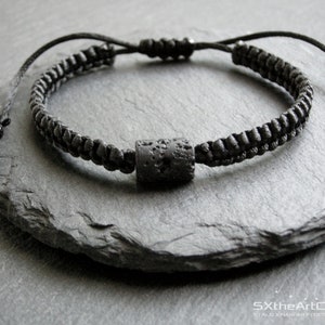 Pode incluir: Pulseira de cord&atilde;o tran&ccedil;ado preto com uma conta de lava preta. A pulseira &eacute; amarrada com um n&oacute; e tem um cord&atilde;o longo para ajustar o ajuste.
