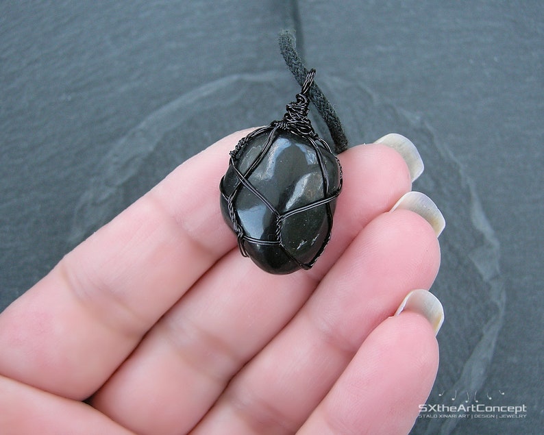 May include: A black stone pendant wrapped in black wire, hanging from a black cord.