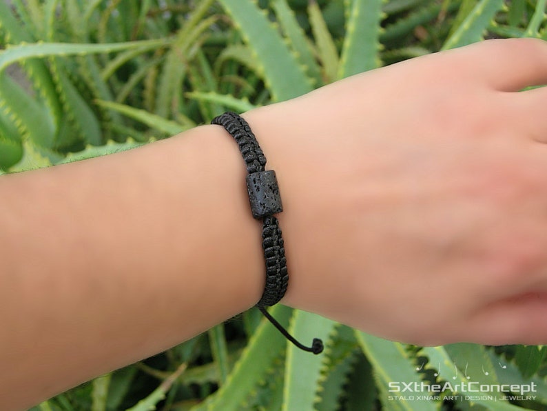 Pode incluir: Um bracelete tran&ccedil;ado preto com uma conta de lava preta. O bracelete &eacute; ajust&aacute;vel e tem um design simples.