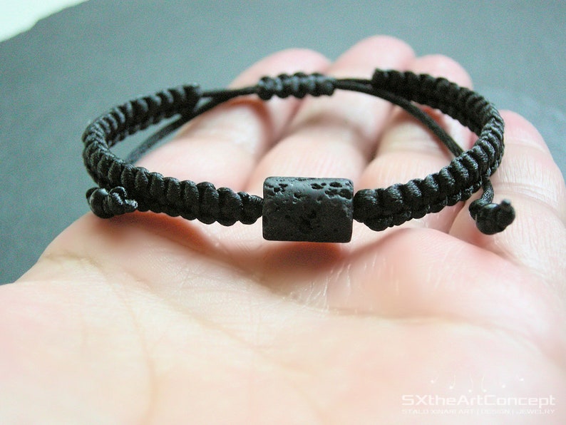 Pode incluir: Um bracelete tran&ccedil;ado preto com uma conta de rocha de lava preta.
