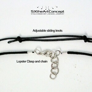 Puede incluir: Un collar de cord&oacute;n negro con nudos deslizantes ajustables y un cierre de langosta y cadena. El texto "SXtheArtConcept" y "STALD XINARI ART | DESIGN | JEWELRY" est&aacute; impreso sobre un fondo blanco por encima del collar. El texto "Nudos deslizantes ajustables" est&aacute; impreso debajo del collar. El texto "Cierre de langosta y cadena" est&aacute; impreso debajo del cierre.