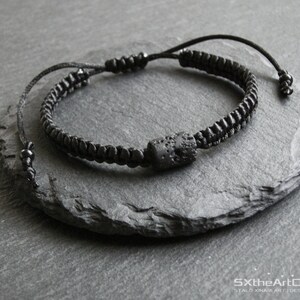Pode incluir: Um bracelete preto com uma conta de lava preta. O bracelete &eacute; feito de um cord&atilde;o tran&ccedil;ado e tem um design simples.