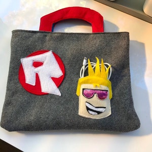 May include: Gray felt tote bag with a red felt R logo and a felt character with yellow hair, pink sunglasses, and a white smile.