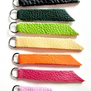 以下が含まれることがあります： 黒、濃い緑、薄い緑、ベージュ、オレンジ、ピンク、紫の金属製のリングが付いた革のストラップが7本あります。