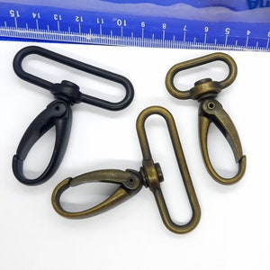 May include: Two swivel clasps, one black and one antique brass. Both clasps have a D-ring and a swivel hook.