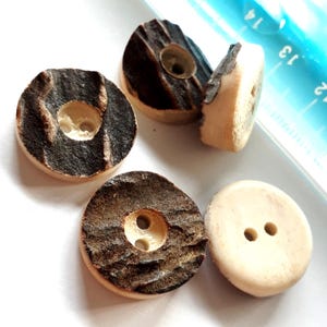 Könnte beinhalten: Fünf runde, braune und weiße Holz-Knöpfe mit jeweils zwei Löchern. Die Knöpfe haben ein natürliches Holzmaserungsmuster.