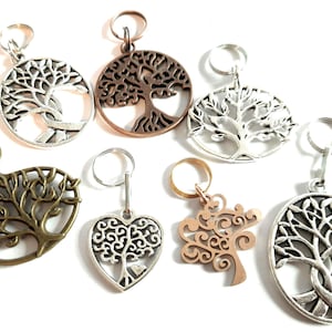 Op de afbeelding: Een set van zeven zilveren en bronzen sleutelhangers met een levensboom-ontwerp. De sleutelhangers hebben verschillende ontwerpen van de levensboom, waaronder een hartvormig ontwerp.