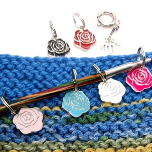 Könnte beinhalten: Ein Set mit sechs bunten rosafarbenen Maschenmarkierern zum Stricken oder Häkeln. Die Marker sind an einem silbernen Ring befestigt und in verschiedenen Farben erhältlich, darunter rosa, blau, weiß und rot.