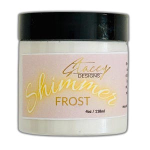 May include: A white jar with a black lid, labeled "Stacey Designs Shimmer Frost." The label is light pink with gold lettering. The jar contains 4oz / 118ml of product.