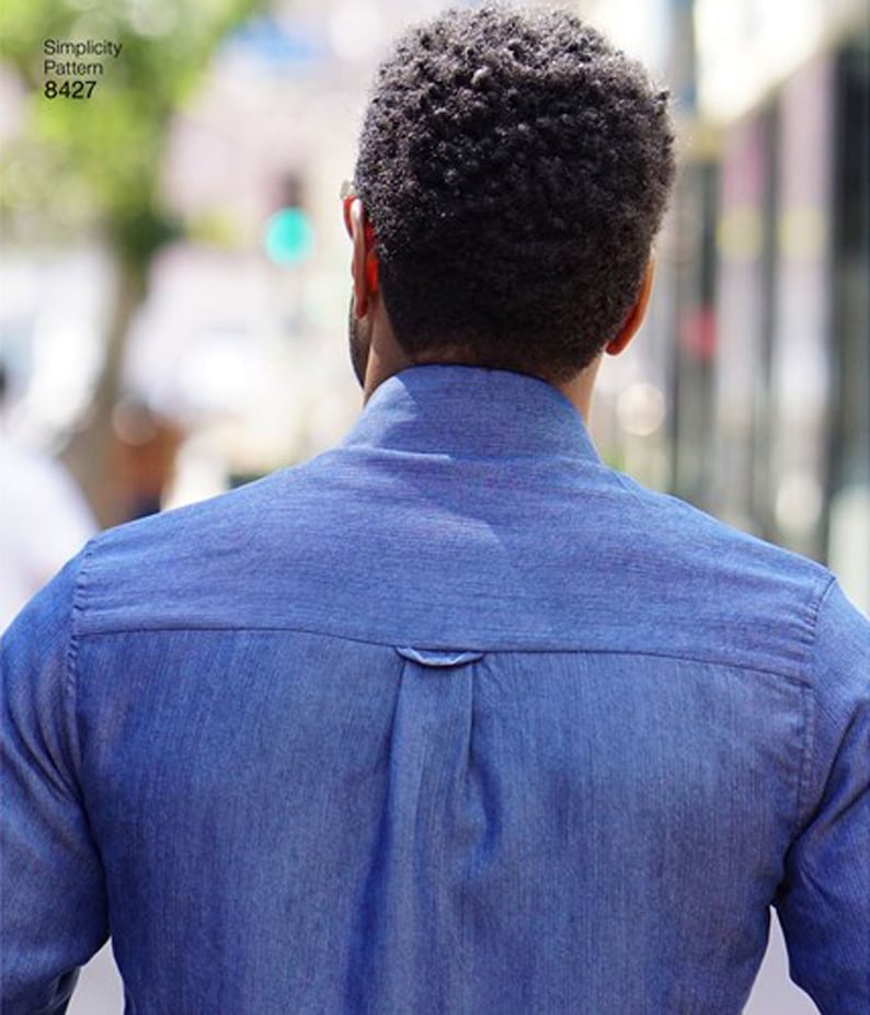 May include: A blue denim shirt with a button-down collar and a yoke detail on the back. The image shows the back of the shirt, with the text "Simplicity Pattern 8427" in the upper left corner.