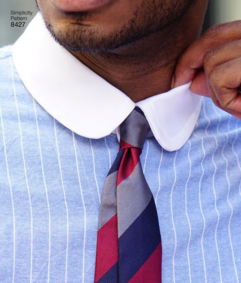 May include: Close-up of a light blue striped shirt with a white collar and a striped tie. The tie features red, gray, and navy blue stripes. The text "Simplicity Pattern 8427" is visible in the upper left corner.