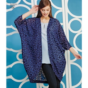 May include: A Simplicity Pattern 1108 open-front kimono-style cardigan featuring a dark blue floral lace pattern, three-quarter length sleeves, and a loose, flowing silhouette worn over a light blue top and dark blue pants.