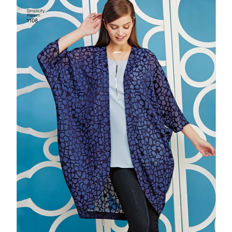 May include: A Simplicity Pattern 1108 open-front kimono-style cardigan featuring a dark blue floral lace pattern, three-quarter length sleeves, and a loose, flowing silhouette worn over a light blue top and dark blue pants.
