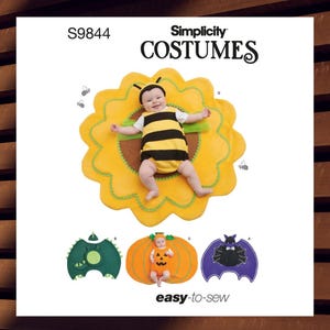 May include: Simplicity Costumes pattern S9844. The image shows a baby dressed as a bee, lying on a yellow flower-shaped mat. Other costume options include a dragon, a pumpkin, and a bat. The text "easy-to-sew" is also visible.